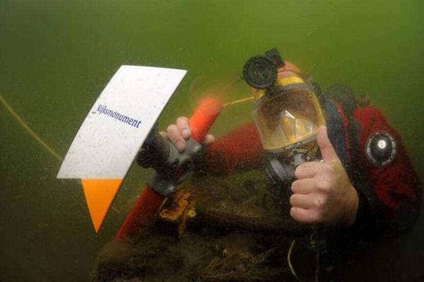 Foto van een duiker met een Rijksmonumenten-bordje
