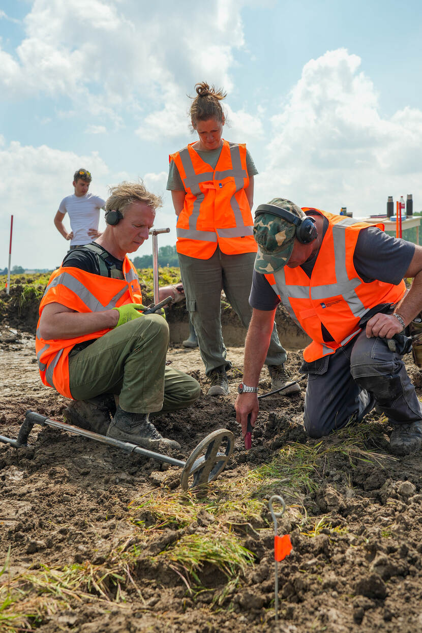 Foto van drie personen in het veld met een metaaldetector, bij de opgraving van de muntschat in Bunnik in 2023