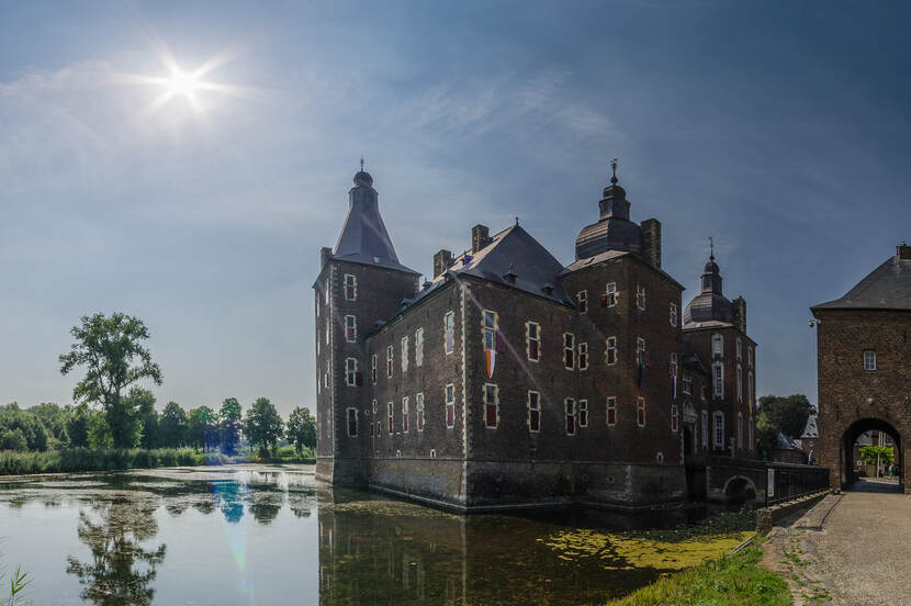 Foto van Kasteel Hoensbroek met torens en de slotgracht op de voorgrond.