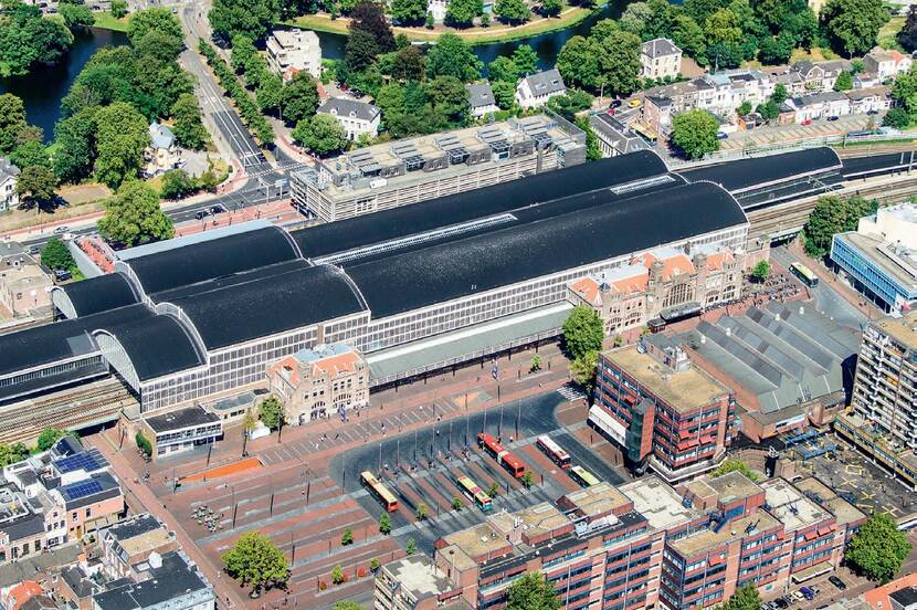 Luchtfoto van het stationsgebied in Haarlem. In het midden is het stationsgebouw zichtbaar. Ten zuiden daarvan het busplatform met daaromheen bebouwing.