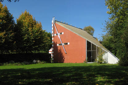 Galerie Waalkens met een grasveld ervoor. De galerie zelf is een driehoek met het rechterpunt verder weg.