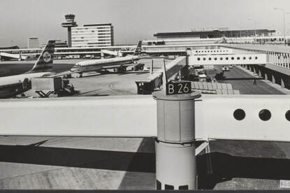 Zwart-wit foto van geparkeerde vliegtuigen en terminals.