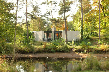 Een huis in het bos met daarvoor een rivier.